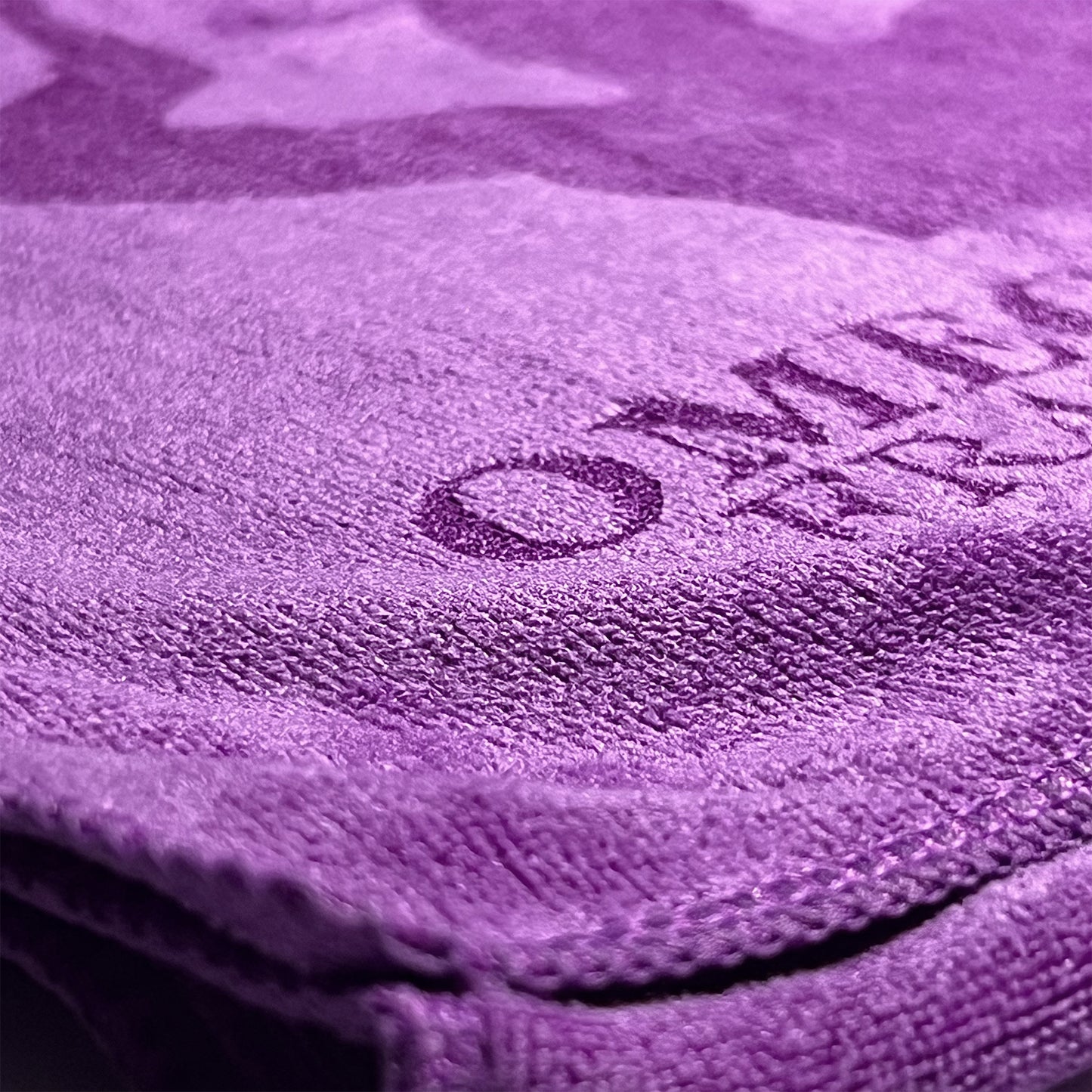 Close-up of a purple microfiber towel with Omega Psi Phi logo on it.