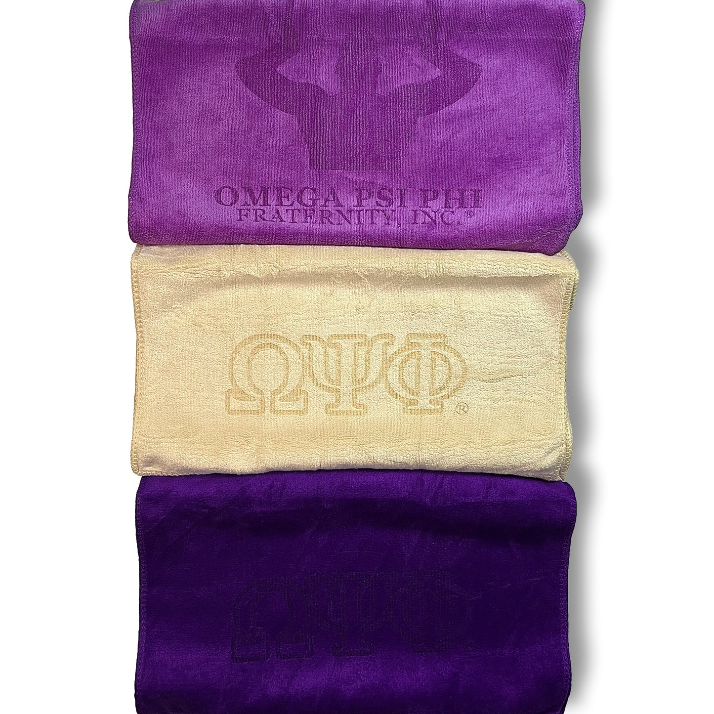 Purple and Old Gold colored towels with Omega Psi Phi fraternity logos on a white background