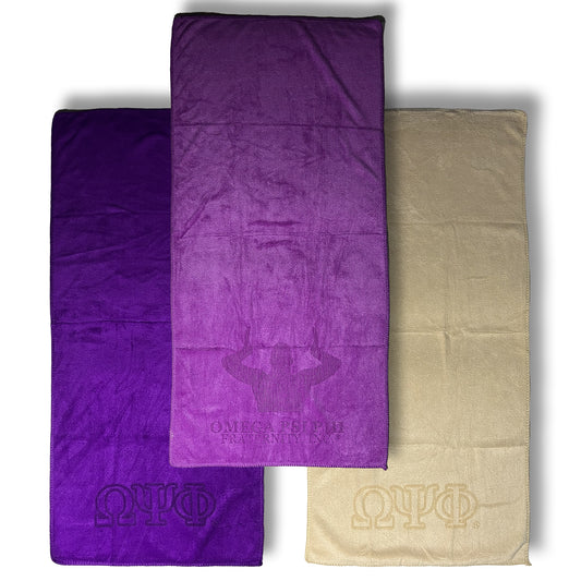Three towels in purple and old gold with Omega Psi Phi logo on a white background