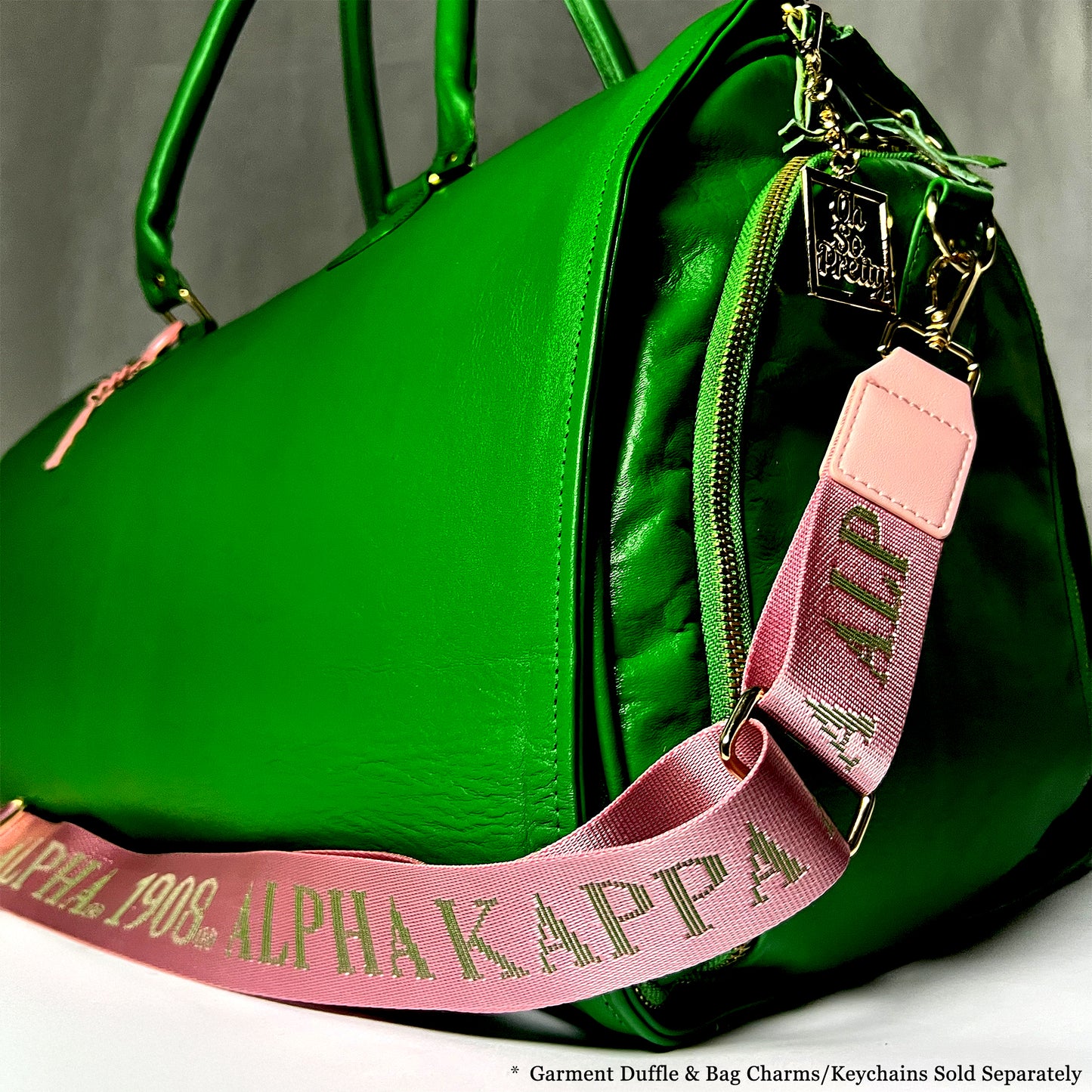 Alpha Kappa Alpha/1908 debossed bag strap featured on a leather green garment duffle bag. Notice: Garment Duffle *& Bag Charms/Keychains Sold Separately.