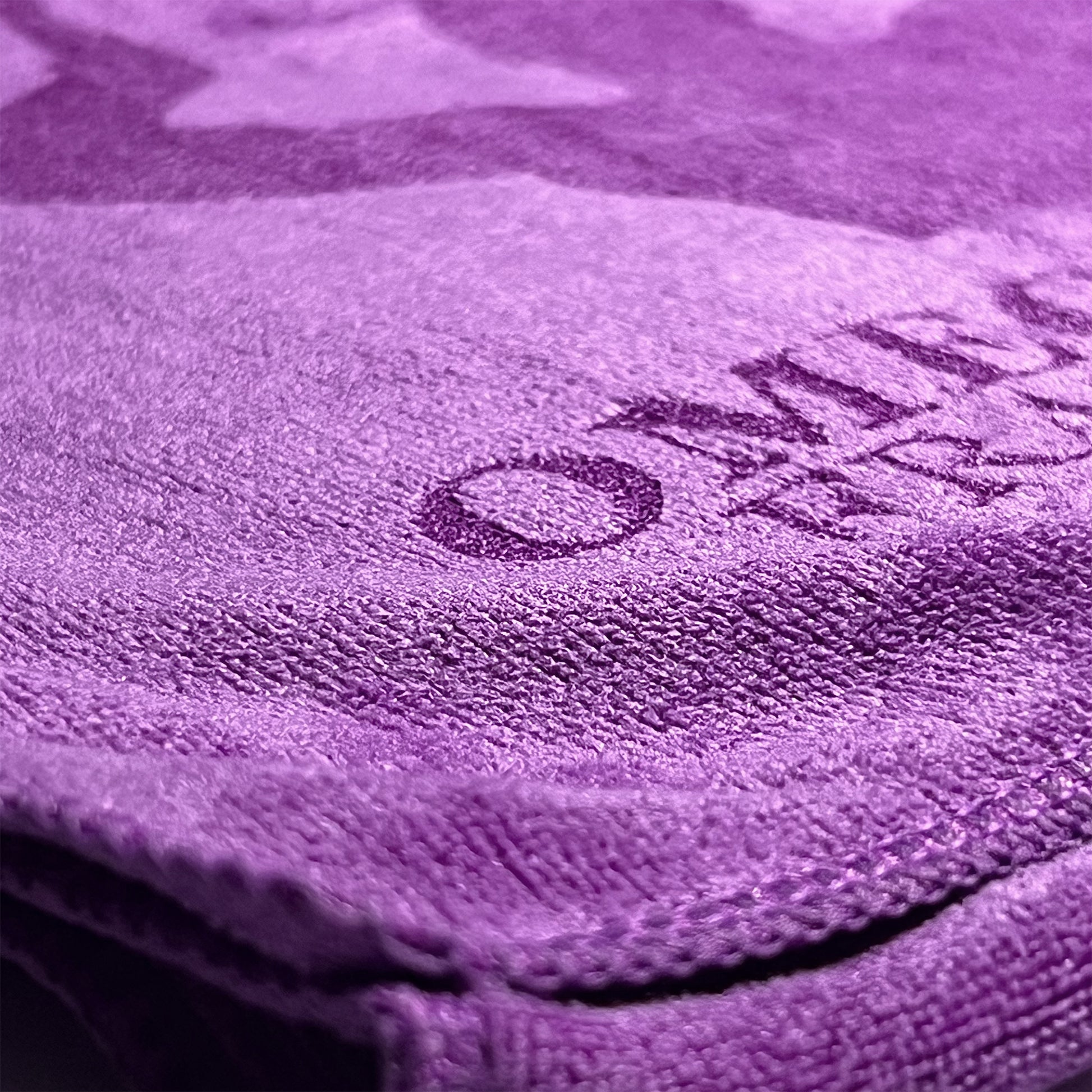 Close-up of a purple microfiber towel with Omega Psi Phi logo on it. 