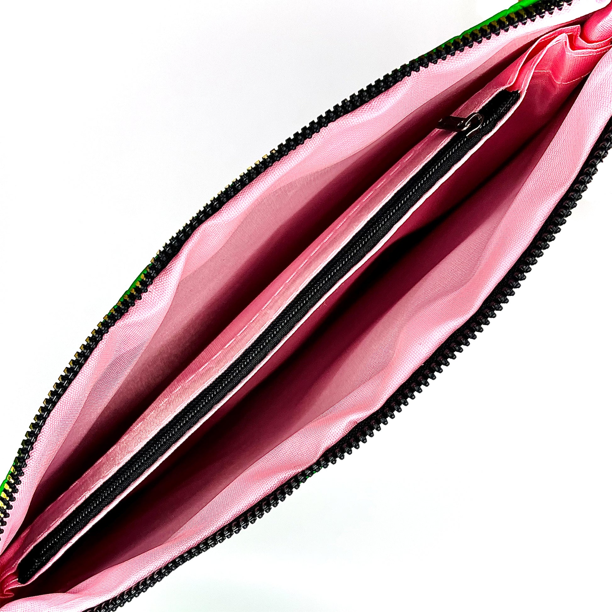Interior view of pink lining inside the Green woven bag with a black zipper pocket on the inside.