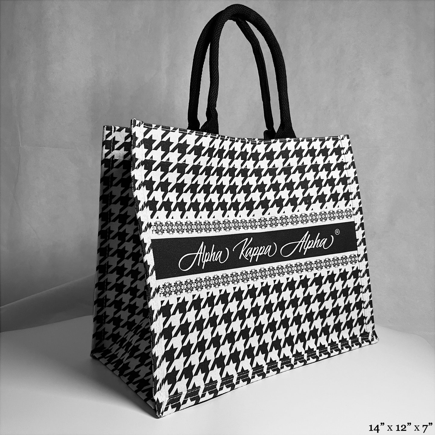 tote bag with black and white houndstooth pattern. Alpha Kappa Alpha text in the center. 