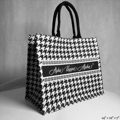 tote bag with black and white houndstooth pattern. Alpha Kappa Alpha text in the center. 