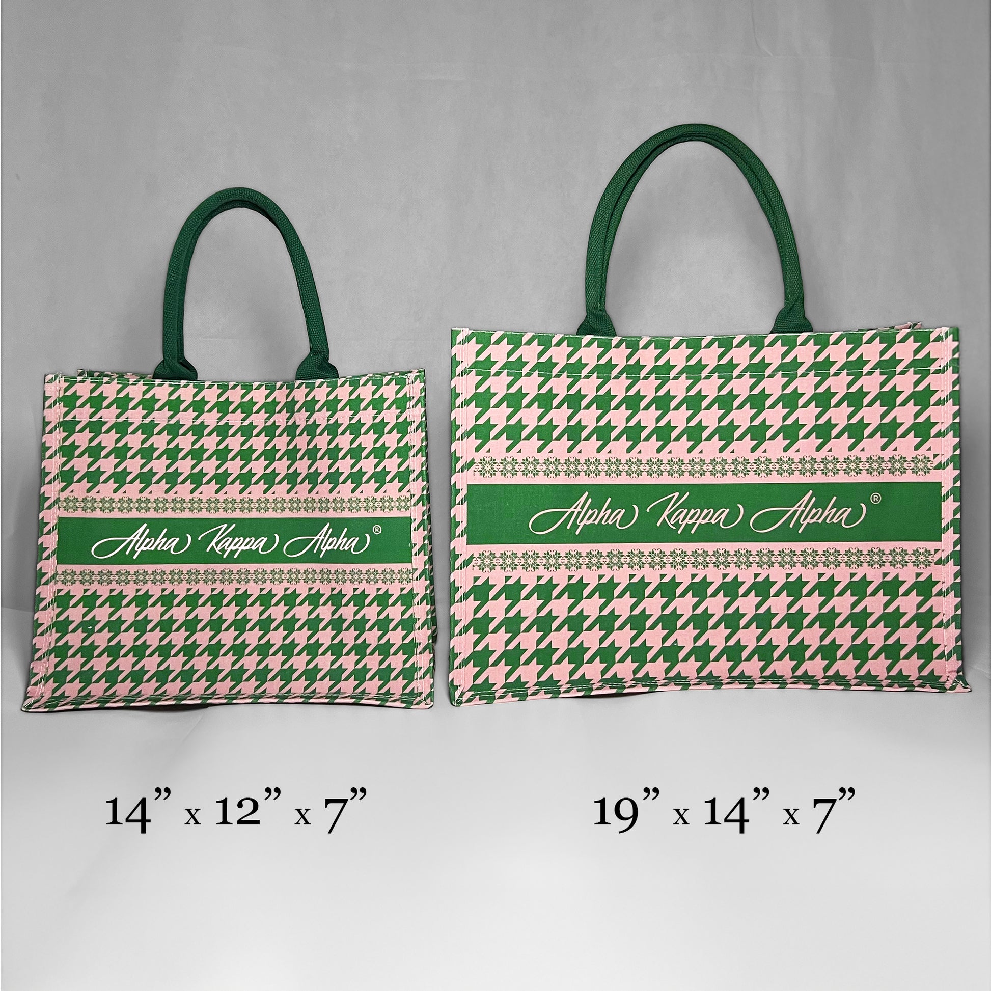 Two tote bags with green and pink houndstooth pattern and 'Alpha Kappa Alpha' text showing the size comparison. The left bag is the smaller version at 14 inches by 12 inches by 7 inches.  The right bag is the larger version at 19 inches by 14 inches by 7 inches.